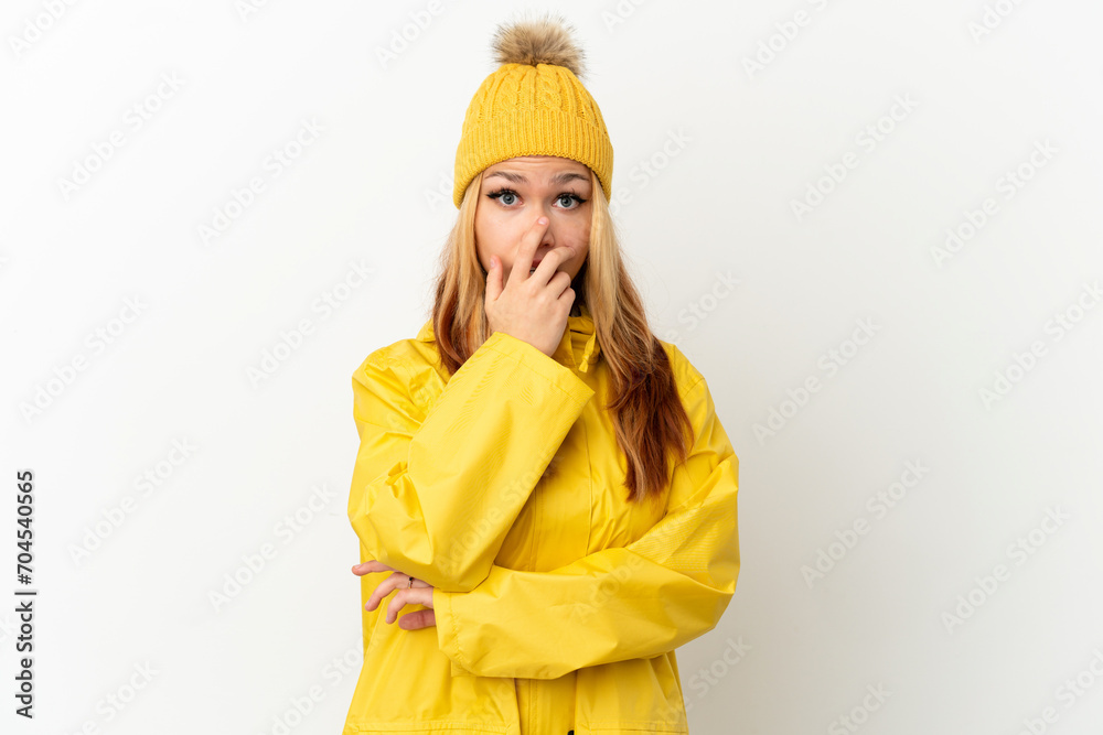 Teenager blonde girl wearing a rainproof coat over isolated white background surprised and shocked while looking right Teenager blonde girl wearing a rainproof coat over isolated white background surprised and shocked while looking right