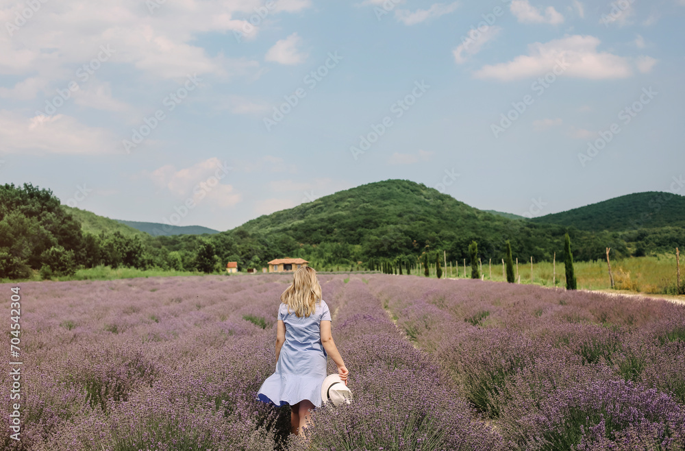 Rear view of woman in dress and white hat in middle of lavender field