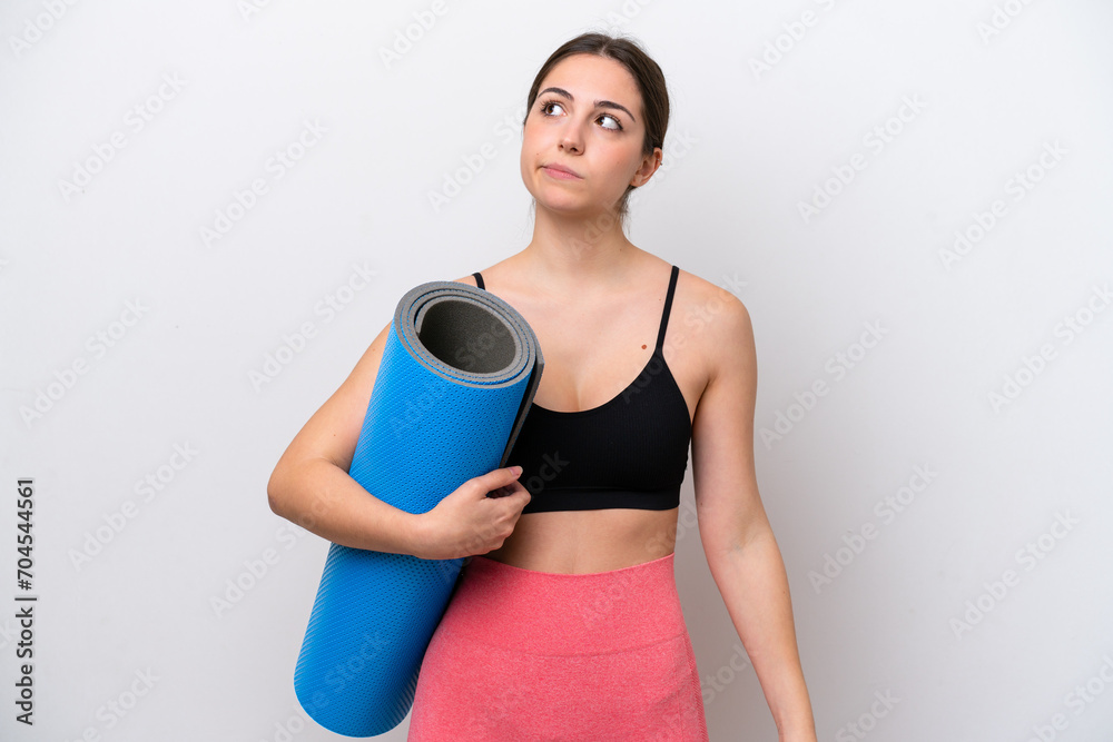 Young sport girl going to yoga classes while holding a mat isolated on white background and looking up Young sport girl going to yoga classes while holding a mat isolated on white background and looking up