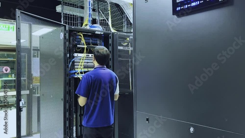 Computer engineer working with supercomputer in data center. Technician connecting cable on server in server room. system administrator setting up server network and doing maintenance.
