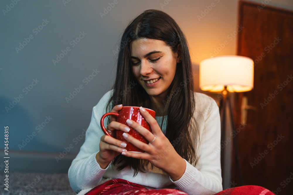 A young girl or woman getting up from bed drinking coffee or tea in blanket cozy room A young girl or woman getting up from bed drinking coffee or tea in blanket cozy room