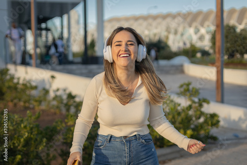 chica joven alegre escuchando música con auriculares por la calle © Rafa