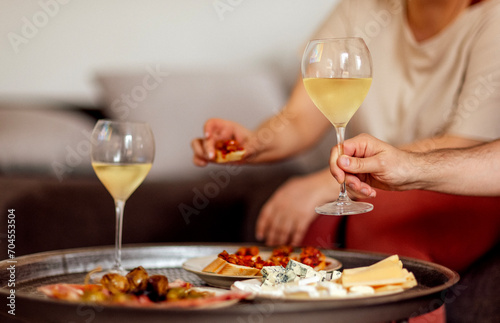 Two glasses of cool champagne and plates with various snacks on a round metal coffee table