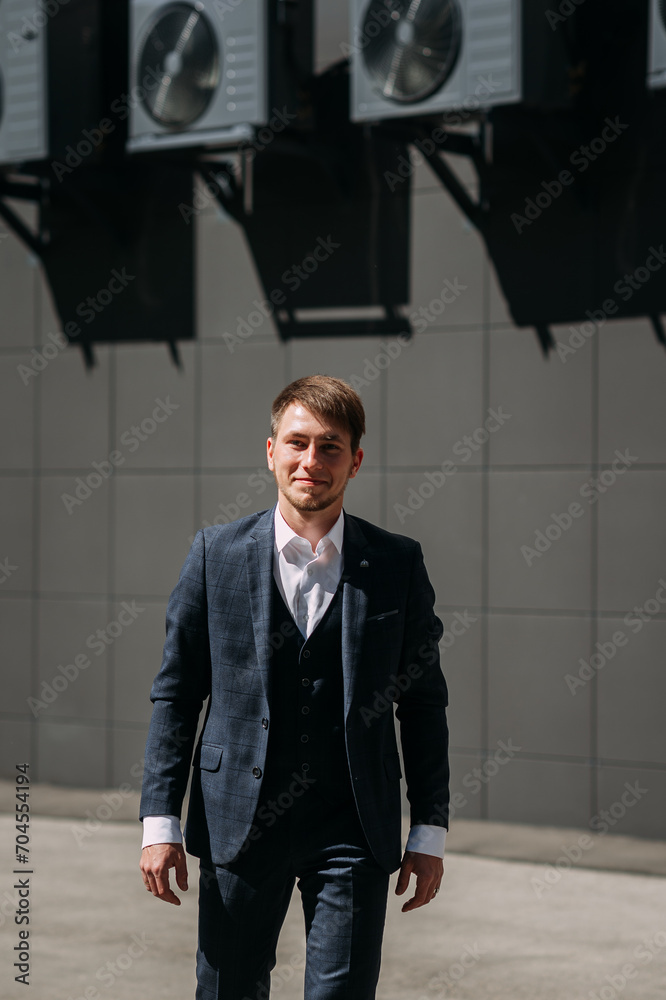 A man in a suit, standing in front of a building 5049.