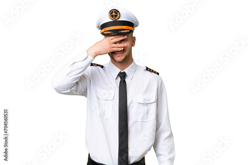 Airplane pilot man over isolated background covering eyes by hands and smiling