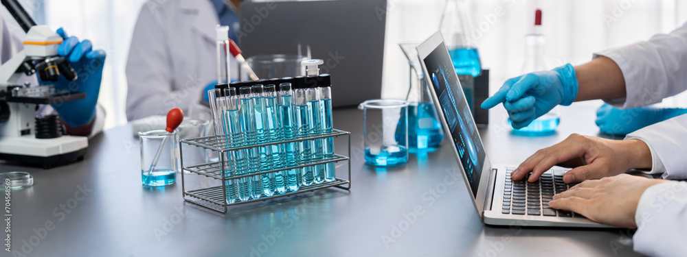 Dedicated group of scientist conduct chemical experiments and research in medical lab as groundbreaking developing for new vaccine drug or antibiotic and studying test result on laptop. Neoteric - obrazy, fototapety, plakaty 