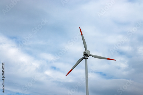 The blades of a wind turbine against the background of a blue cloudy sky