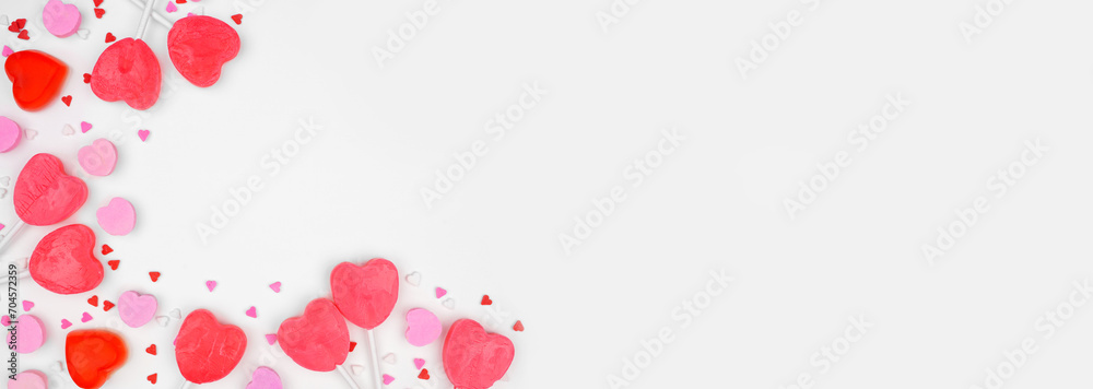 Valentines Day corner border of candy hearts and sprinkles. Above view on a white banner background. Copy space.