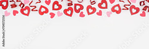 Valentines Day top border of hearts and ribbon. Above view on a white banner background. Copy space.