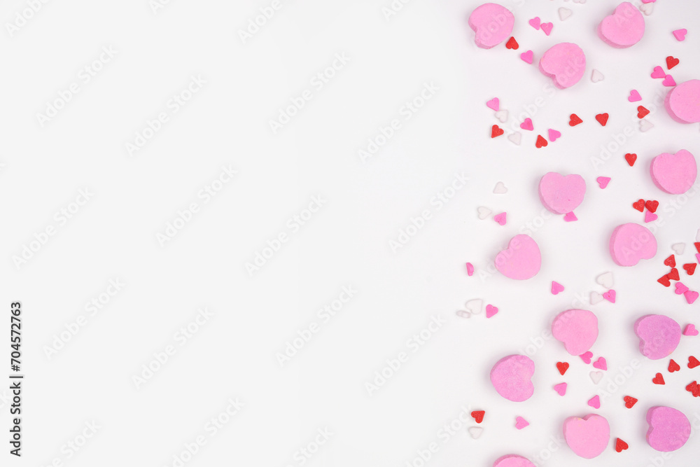 Valentines Day side border of candy hearts and sprinkles. Top view on a white background. Copy space.