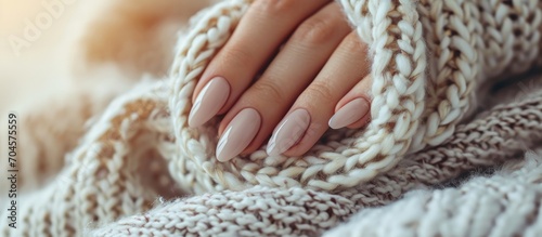 Beautifully manicured nails on a cozy sweater with a scarf. Nail care concept.