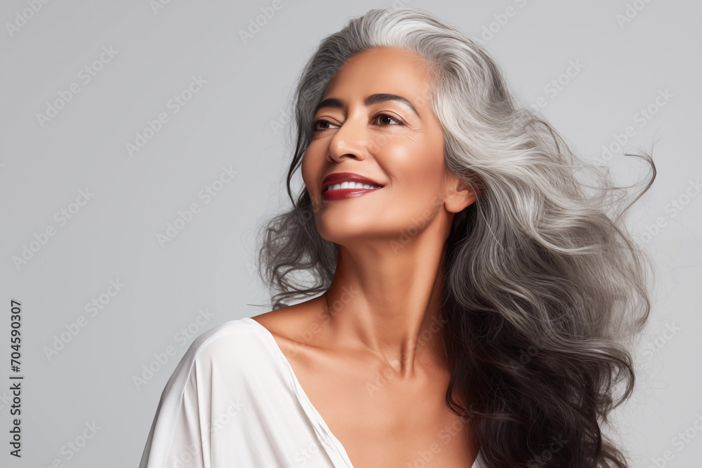 Gorgeous senior older smiling Indian woman with natural makeup on grey background with copy space Gorgeous senior older smiling Indian woman with natural makeup on grey background with copy space
