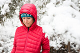 A young woman in a red jacket, hiking in the snow.