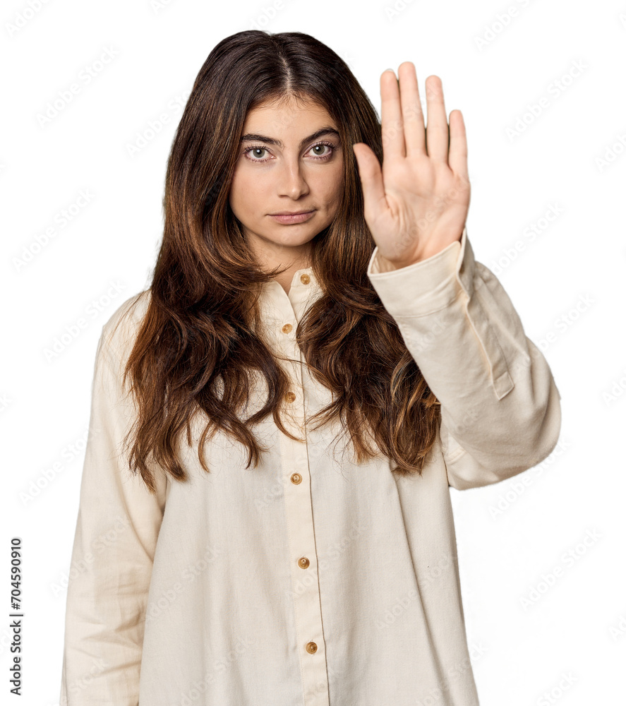 Young Caucasian woman in studio setting standing with outstretched hand showing stop sign, preventing you. Young Caucasian woman in studio setting standing with outstretched hand showing stop sign, preventing you.