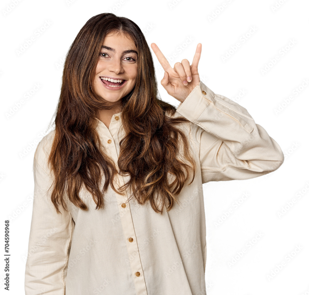 Young Caucasian woman in studio setting showing a horns gesture as a revolution concept. Young Caucasian woman in studio setting showing a horns gesture as a revolution concept.