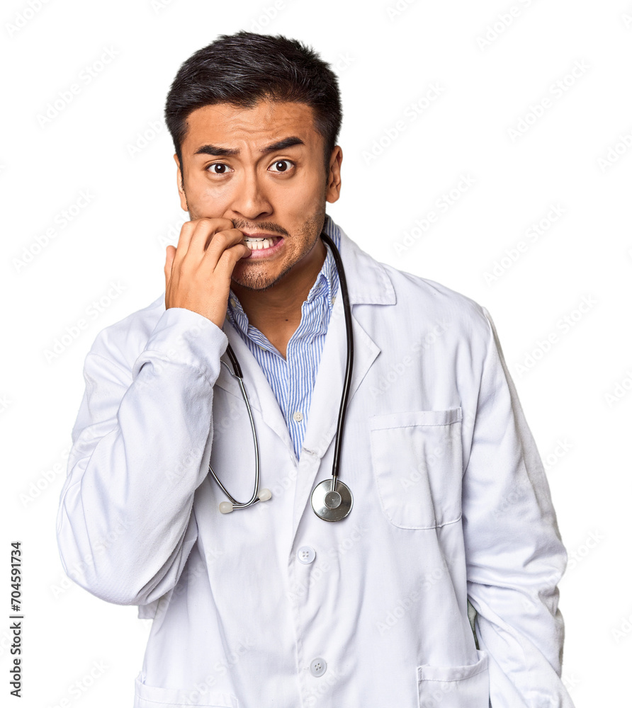 Young Chinese man as a medical doctor in studio biting fingernails, nervous and very anxious. Young Chinese man as a medical doctor in studio biting fingernails, nervous and very anxious.