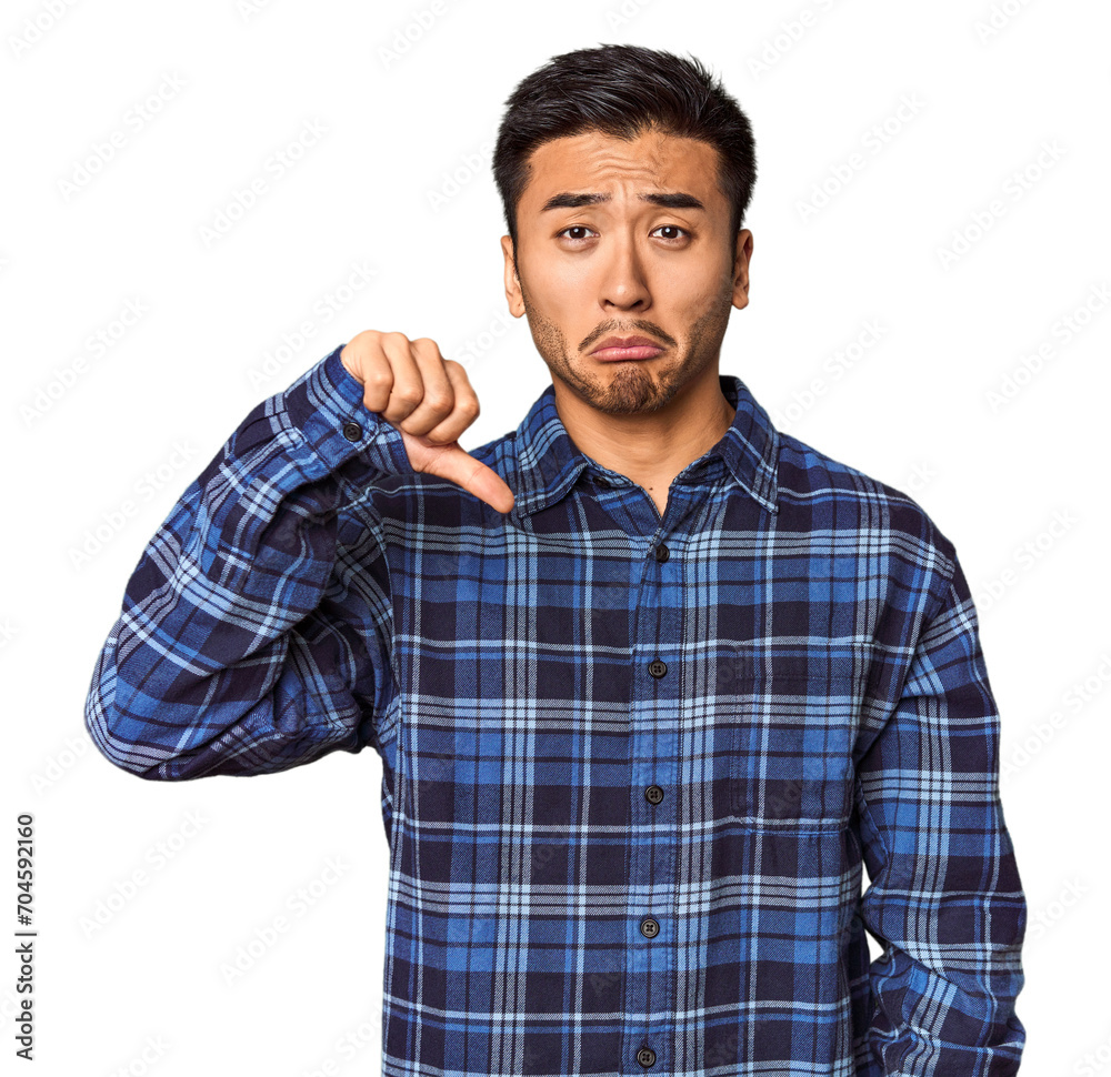 Young Chinese man in studio background showing a dislike gesture, thumbs down. Disagreement concept. Young Chinese man in studio background showing a dislike gesture, thumbs down. Disagreement concept.