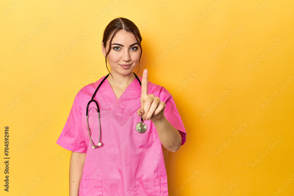 Nursing assistant in yellow background showing number one with finger. Nursing assistant in yellow background showing number one with finger.