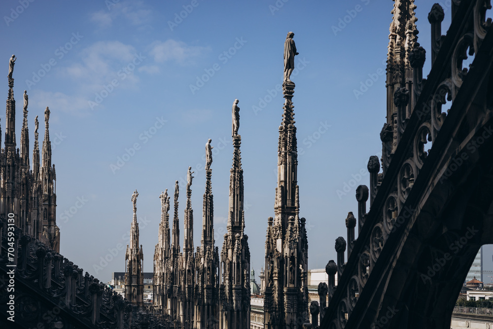 Roof of Milan Cathedral Duomo di Milano with Gothic spires and white marble statues. Top tourist attraction on piazza in Milan, Lombardia, Italy. Gothic architectural fragment Roof of Milan Cathedral Duomo di Milano with Gothic spires and white marble statues. Top tourist attraction on piazza in Milan, Lombardia, Italy. Gothic architectural fragment