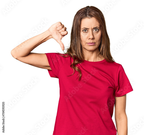 Middle-aged woman portrait in studio setting showing a dislike gesture, thumbs down. Disagreement concept.