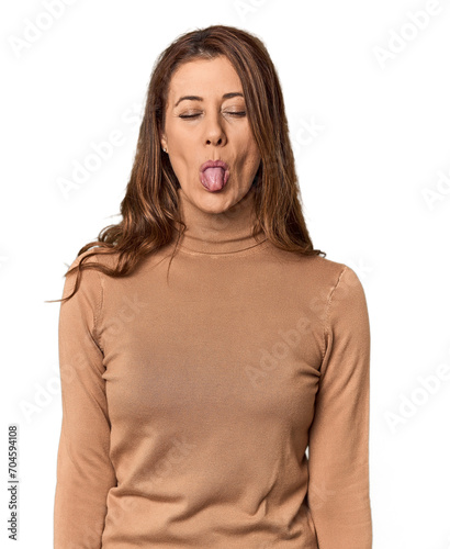 Middle-aged woman portrait in studio setting funny and friendly sticking out tongue.