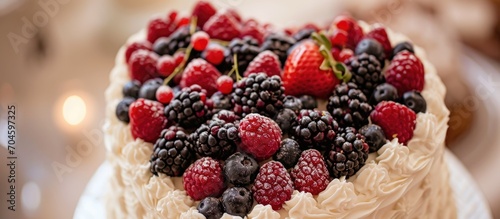 A wedding cake in the shape of a heart  adorned with berries and decorations  captured in a closeup shot.