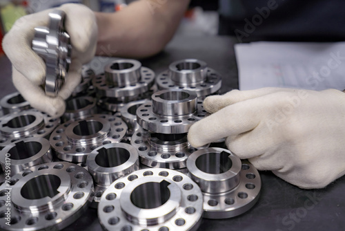 A worker inspects and sorts round parts with holes.