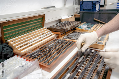 The worker selects gauge blocks to obtain the required control size of the part being manufactured and adjusts the measuring tool of a CNC metal-cutting machine.