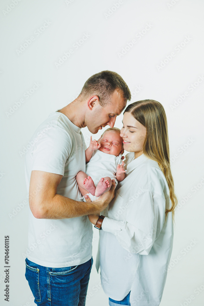 Happy mother and father hugging their newborn baby. Parents and a smiling child in their arms. A young family with a newborn baby. Happy mother and father hugging their newborn baby. Parents and a smiling child in their arms. A young family with a newborn baby.
