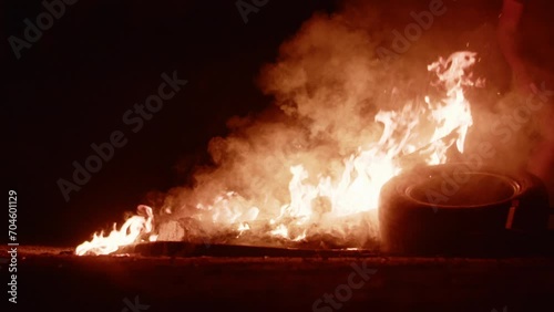 Flames and smoke from tires on the fire at night. People on protest riot