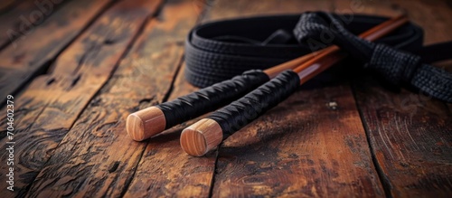Nunchaku, black belt, and gi on wood floor (martial arts) photo