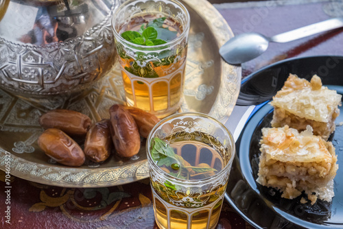 Vasos de té marroquí con dátiles y dulces de pistacho con miel photo