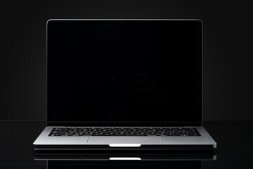 Open laptop with black screen against black background