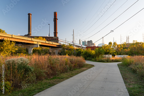 Lovely urban greenway walking trail path through city at sunset with city buildings in background