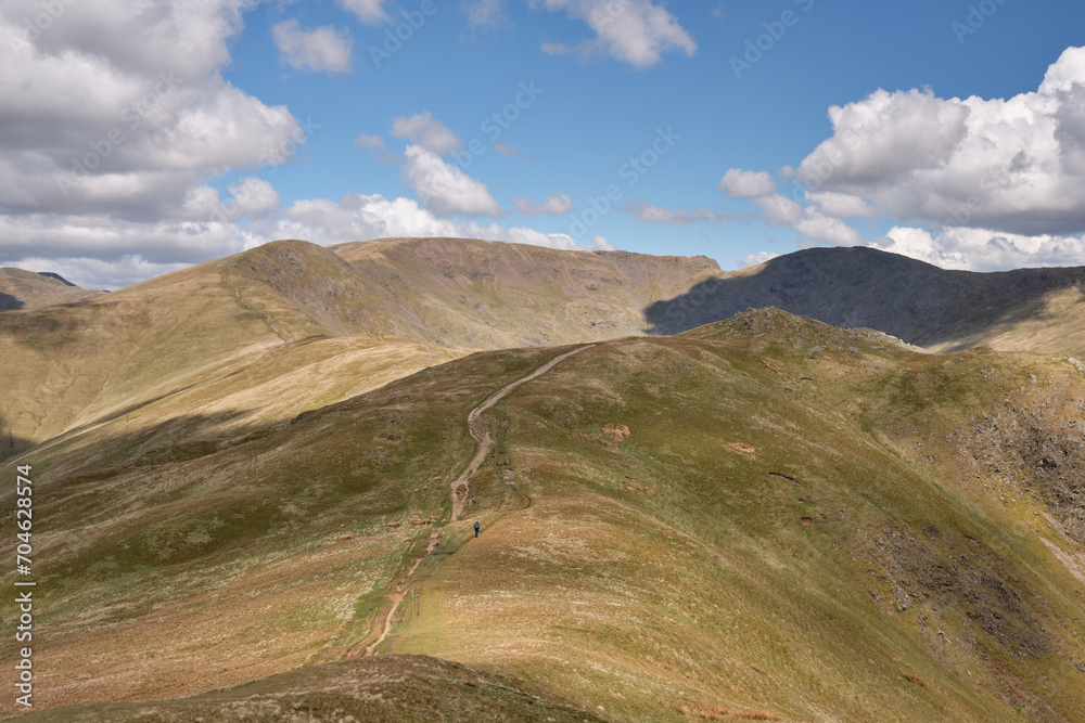 The summit of Fairfield seen as a hiker ascends Heron Pike on the Fairfield Horseshoe, Lake District, UK