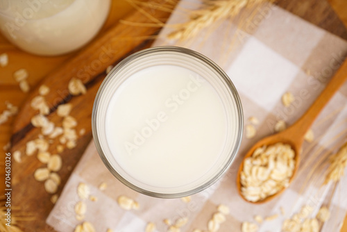 Glass and jug of fresh milk on wooden table against color background. Top view.