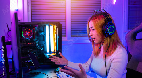 Game over you lose. Angry Asian gamer wearing gaming headphones playing joystick console video game on computer PC neon light at home feeling sad disappointed about game losing, player unhappy E-Sport