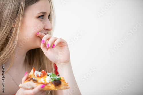 Close-up profile shot of a happy girl eating pizza.