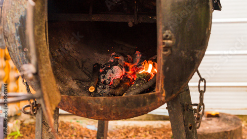 Parrilla oxidada y desgastada del campo magallánico llamada chulengo, con el fuego en su interior que se usa para cocinar o calentar. El fuego se sitúa en el centro de la parrilla. photo