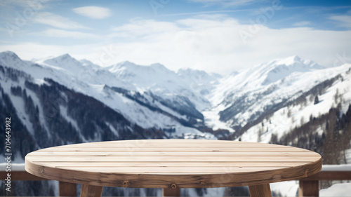 Empty wooden table to display products, round wooden table in front of blurred snowy mountain background, winter packshot, beautiful nature in winter, switzerland, norway, alps