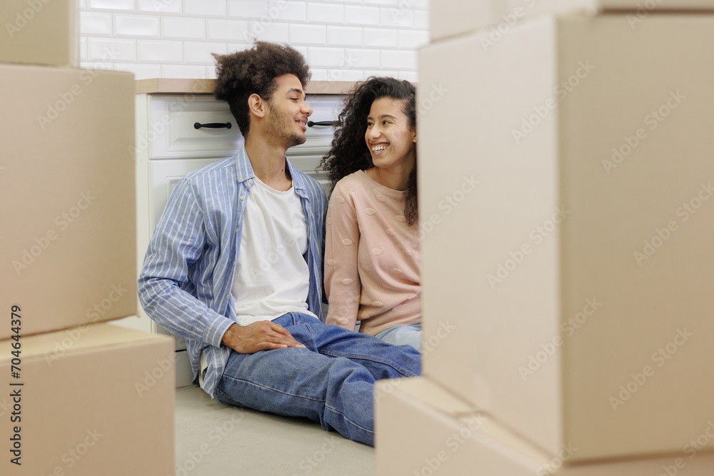 happy young African American couple is moving new home. man and woman are sitting among cardboard boxes talking about mortgage or rental property. moving movers service. renewal of lease agreement happy young African American couple is moving new home. man and woman are sitting among cardboard boxes talking about mortgage or rental property. moving movers service. renewal of lease agreement