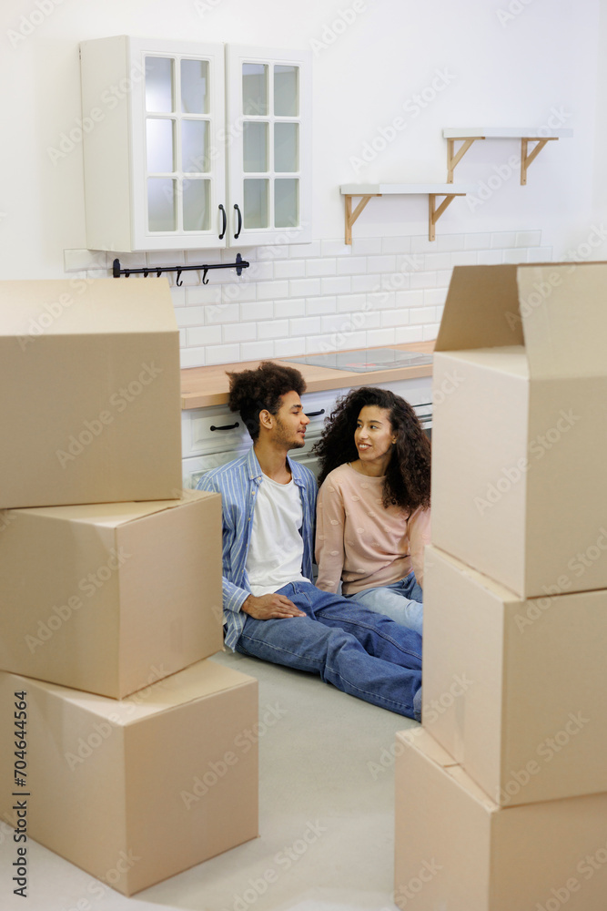 happy young African American couple is moving new home. man and woman are sitting among cardboard boxes talking about mortgage or rental property. moving movers service. renewal of lease agreement happy young African American couple is moving new home. man and woman are sitting among cardboard boxes talking about mortgage or rental property. moving movers service. renewal of lease agreement