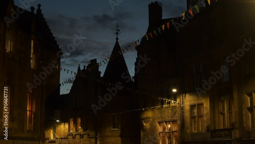 Festive decorations in an old street in historic city of Edinburgh at twilight. Colourful bunting flags sway in the light evening wind. Beautifully illuminated facades of picturesque stone buildings. photo
