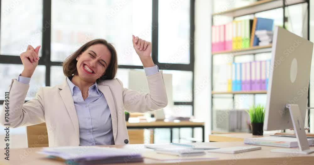 Cheerful professional woman laughs looking at computer monitor at desk in office
