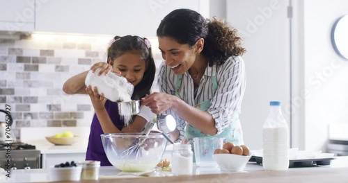 Home, baking and family with recipe, playing and love with happiness, activity and hobby. Mother, childhood and kid with mama, girl or utensils with ingredients, measurement cup and bowl in a kitchen photo