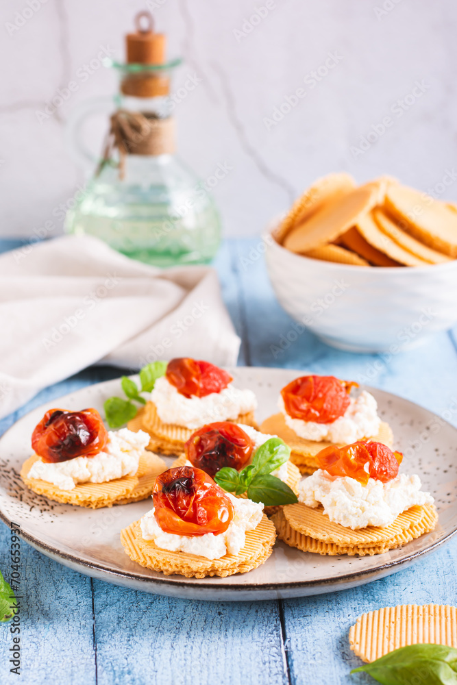 Bruschetta on crispbread with ricotta and baked tomatoes on a plate on the table vertical view Bruschetta on crispbread with ricotta and baked tomatoes on a plate on the table vertical view