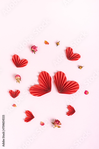 A pair of decorative paper hearts are surrounded by hearts and dried flowers vertical view