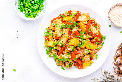 Stir fryed chicken slices with fresh pineapple, paprika, chives, soy sauce and sesame seeds. Asian cuisine dish. White table background, top view