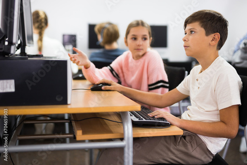 Portrait of a ten-year-old schoolboy studying at a computer in the classroom at a informatics lesson with classmates