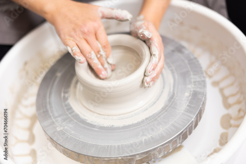 potter's wheel rotates and master creates future work of pottery from clay photo
